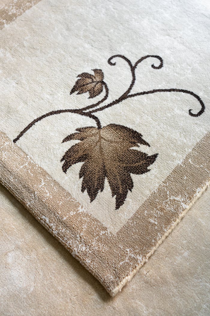 services-01 Close-up of an elegant beige rug featuring a detailed leaf pattern.
